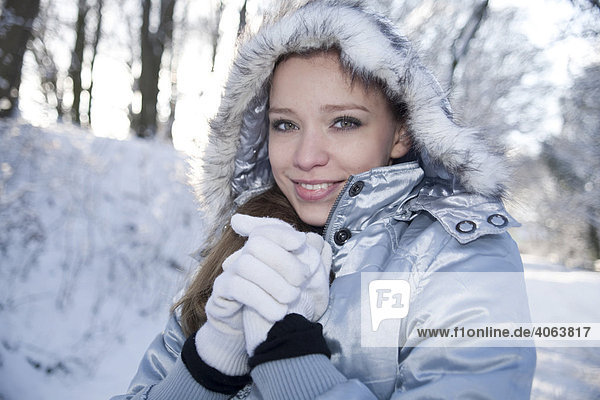 Portrait of a young woman wearing a hat and gloves in wintery landscape  freezing