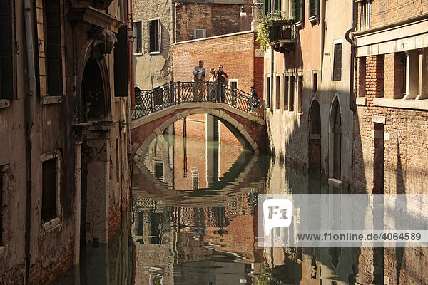 Eine Brücke spiegelt sich im Kanal in Venedig  Italien  Europa