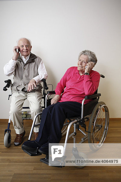 Senioren telefonieren mit Handys im Rollstuhl