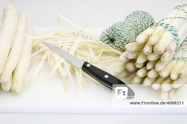 Weißer Spargel  ungeschält und geschält in Portionen gebunden  Bindeschnur  Spargelschalen  Messer