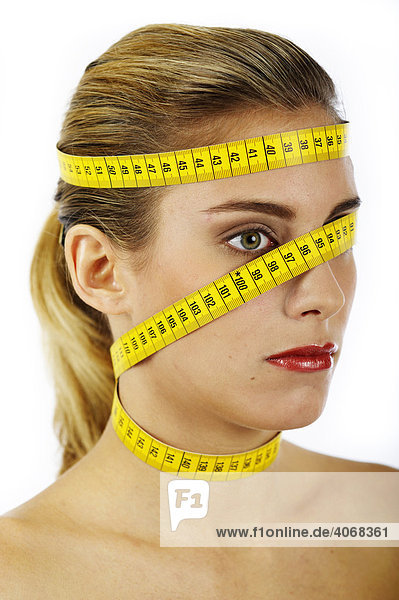 Young woman with measuring tape wrapped around her head and neck
