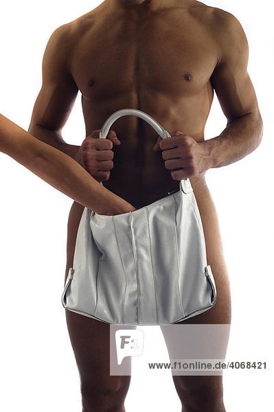 Young naked man holding a handbag in front of his genitals  hand reaching into the handbag