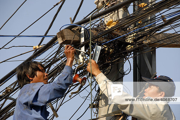 Electrification without safety measures  electricians working in a tangle of electric cables  Vientiane  Laos  Asia