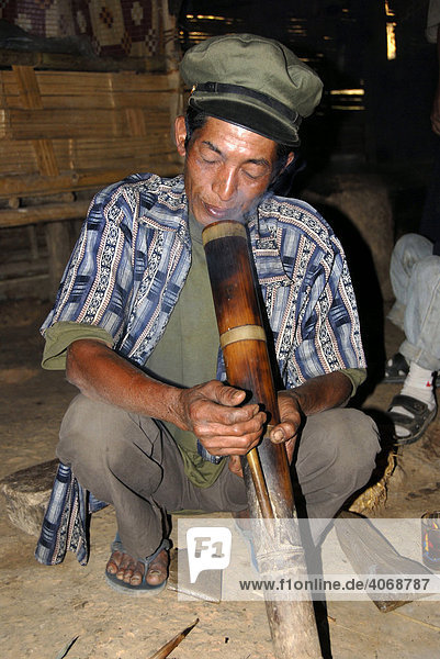 Laote der Phunoi Ethnie mit Schirmmütze raucht Wasserpfeife Bong Ban Khounoum Louang Phongsali Provinz Laos Südostasien