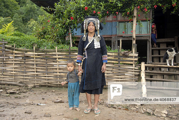 Mutter der Akha Phixo Ethnie in traditionelle Tracht gekleidet hält Kind an der Hand  Ban Phapoun Mai  Phongsali Provinz  Laos  Südostasien