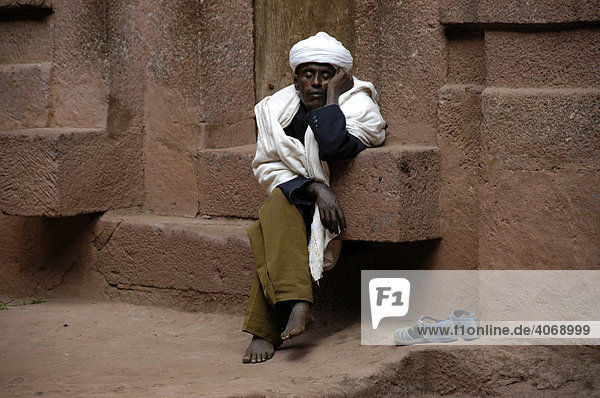 Mann dozing on the steps of a monolithic church  Lalibela  Ethiopia  Africa