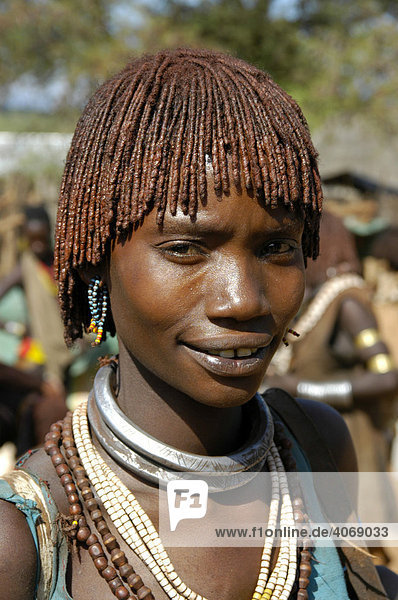 Young woman wearing red clay in her hair and earrings  portrait  at the markets in Dimeka  Ethiopia  Africa
