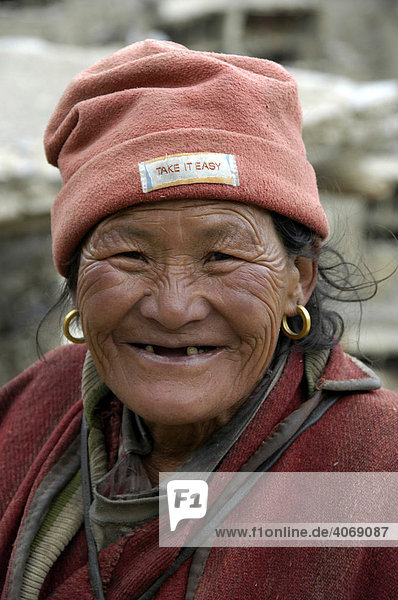Portrait  lächelnde Tibeterin trägt Mütze mit Slogan Take it easy  Phu  Annapurna Region  Nepal  Asien
