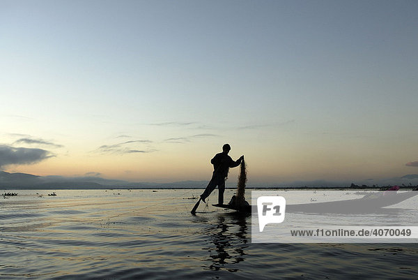 Burmese rowing his boat using one leg whilst fishing  Inle Lake  Myanmar  Burma  South East Asia