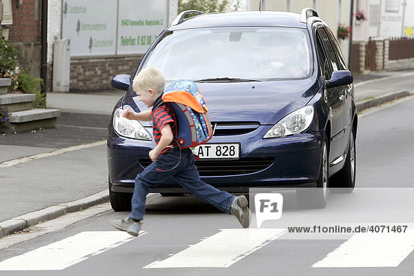 Schoolchild running over a pedestrian crossing while a car is waiting  Bayreuth  Bavaria  Germany  Europe