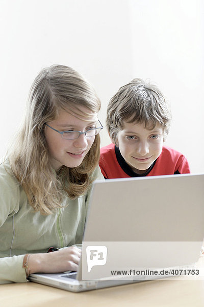 Ein Mädchen  13 Jahre alt  und ihr Bruder  10 Jahre alt  sitzen vor einem Laptop
