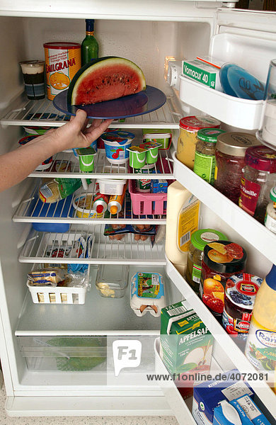 Frau räumt Kühlschrank ein in der Küche