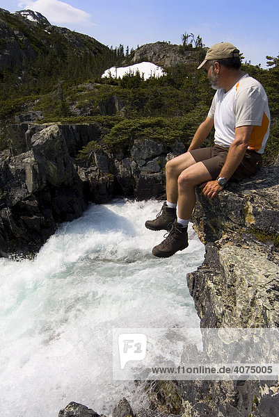 Hiker sitting  resting over water fall  Chilkoot Trail  Chilkoot Pass  British Columbia  B.C.  Canada  North America