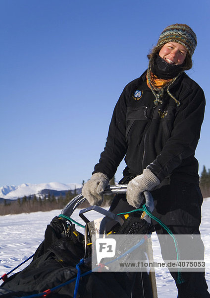 Young woman enjoying a dog sled ride on the frozen Yukon River  Yukon Territory  Canada  North America