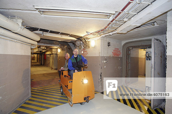 Employees driving an electric trolley through the corridors in the museum of the former Marienthal government bunker near Ahrweiler  Rhineland-Palatinate  Germany  Europe