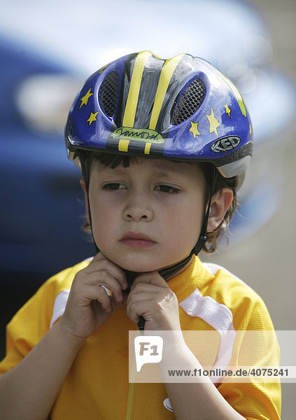 Five-year-old boy putting a bicycle helmet on