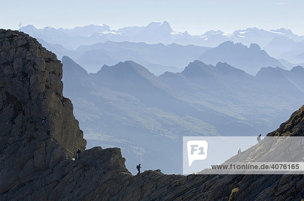 Hikers ascending towards the summit of Saentis Mountain in front of Churfirsten mountains and the Glarus Alps  Switzerland  Europe