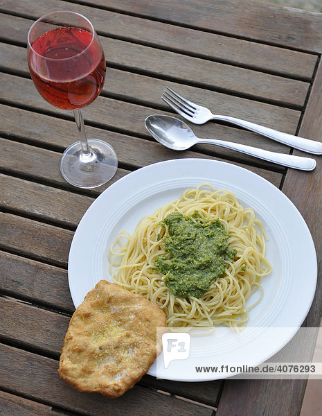 Ein Teller mit Spaghetti mit Pesto und ein Glas Rotwein auf einem Holztisch bei Casale  Toskana  Italien  Europa