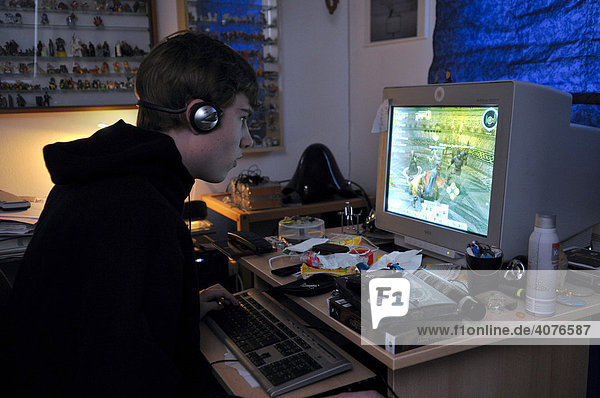 Jugendlicher sitzt im abgedunkelten Raum und spielt am Computer Online Rollenspiele