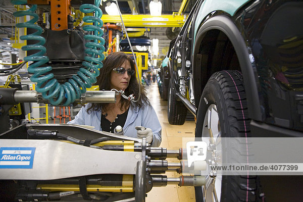 Ein Arbeiter zieht in einem General Motors Montagewerk  welches Buick  Saturn  und GMC-Fahrzeuge produziert  am Fließband Radmuttern an einem Reifen fest  Lansing  Michigan  USA