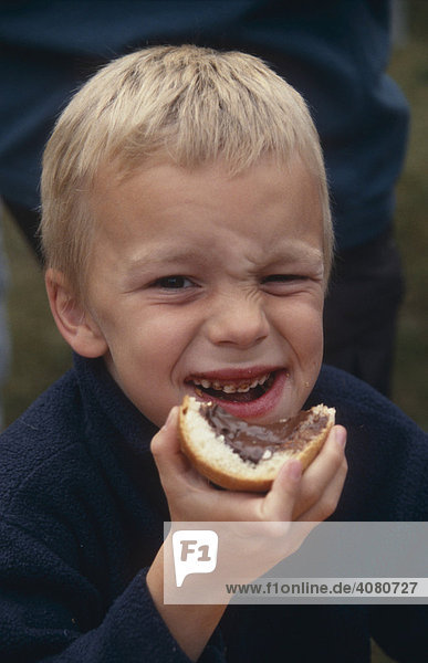 Junge  sechs Jahre alt  isst ein Brötchen mit Nutella