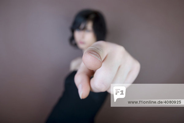 Junge dunkelhaarige Frau zeigt mit dem Finger
