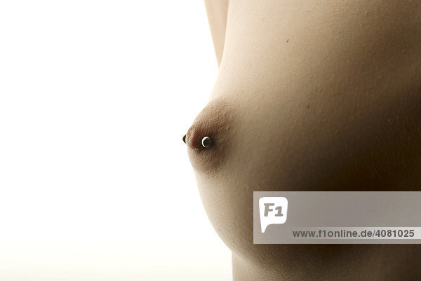 Woman's bare breast  nipple piercing in backlight