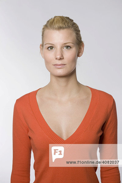 Frontales Portrait einer jungen Frau im orangenen Pullover