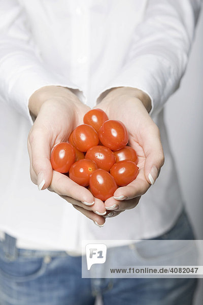 Frau hält viele Tomaten in beiden Händen