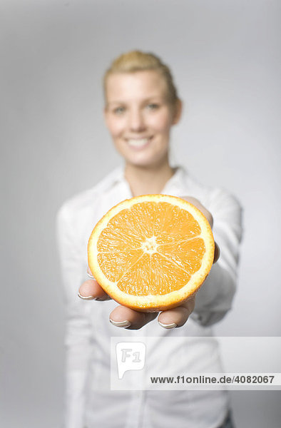 Blonde Frau hält eine aufgeschnittene Orange