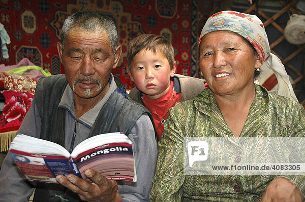 Nomaden Mann Frau und Kind lesen im Lonely Planet guidebook in ihrer Jurte Kharkhiraa Mongolischer Altai bei Ulaangom Uvs Aimag Mongolei