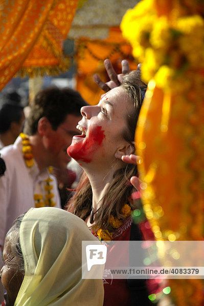 Junge westliche Frau mit roter Farbe im Gesicht lacht bei einer Party Fest auf der Straße Jaipur Holi Festival Rajasthan Indien