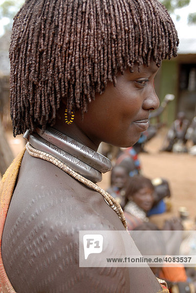 Frau vom Volk der Hamar mit typischer Lehm Haarfrisur mit Schmucknarben auf der Schulter auf dem Markt von Dimeka Äthiopien