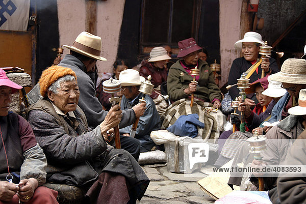 Many Tibetan pilgrims sit in a backyard with prayer wheels Lhasa Tibet China