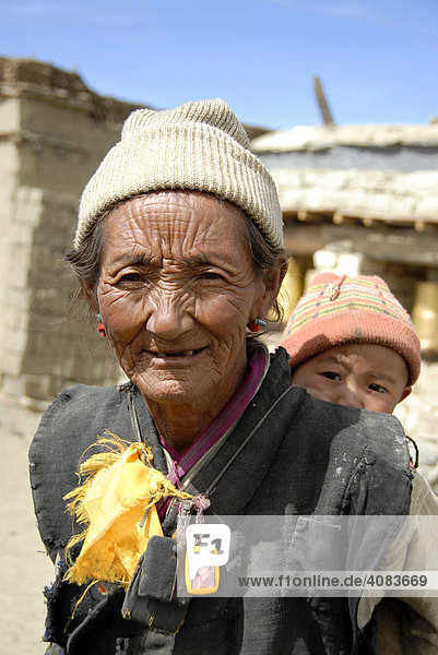 Portrait old woman carries baby on her back Ra Chu village Tibet China
