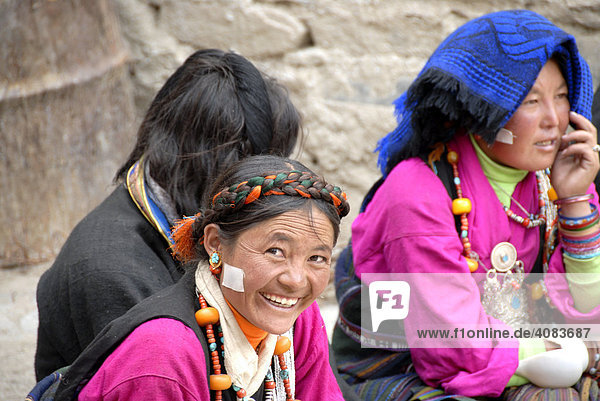 Lachende tibetische Pilgerinnen in Tracht sitzen nebeneinander im Kloster Rongbuk Tibet China