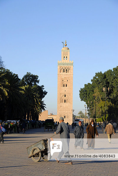 Mann schiebt eine Karre vor Minarett der Koutoubia Moschee Place de Foucauld Djemaa el Fna Marrakech Marokko