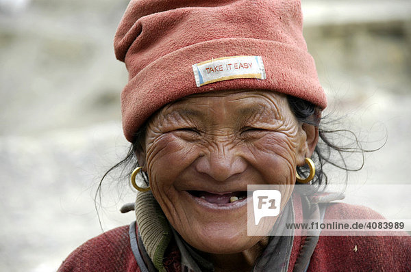 Portrait alte Frau mit Fleecemütze mit Schild Take It Easy Phu Nar-Phu Annapurna Region Nepal