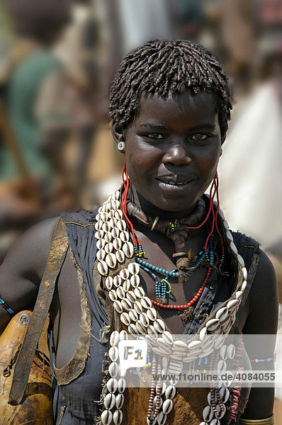 Junge Frau mit Kauri Muschelkette und vielem weiterem Schmuck Markt in Keyafer Äthiopien