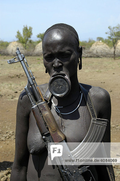 Woman with a plate lip carrying a Kalaschnikow gun of the Mursi people near Jinka Ethiopia