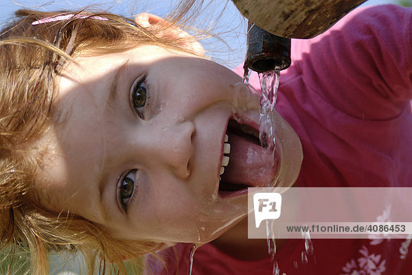 Kind beim wasser trinken aus einem Brunnen Erfrischung
