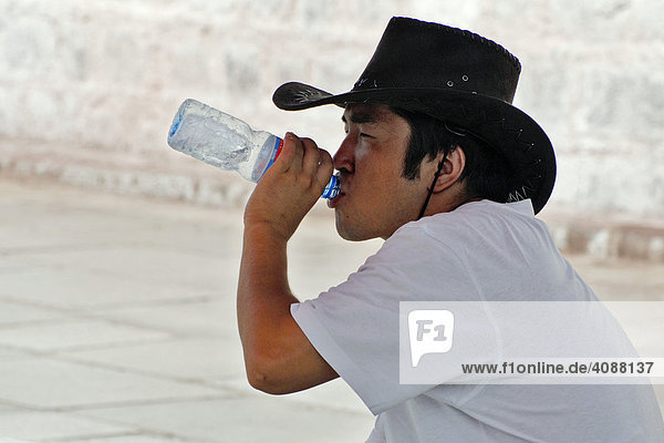 Young male Tibetan with cowboy hat  drinking water  Lhasa  Tibet