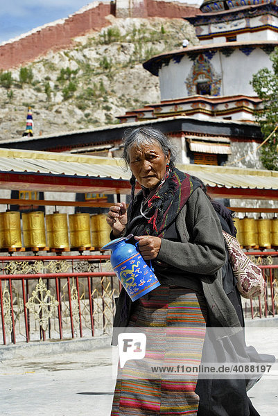 Pilgerin mit Teekanne vor Gebetsmühlen  Pälkhor Chöde Kloster in Gyantse  Tibet