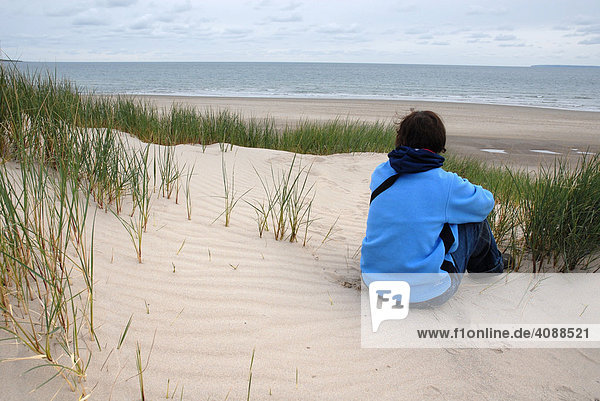 Frau sitzt in Sanddünen  Blick auf das Meer  Harlech  Snowdonia Nationalpark  Gwynedd  Nord Wales  Großbritannien