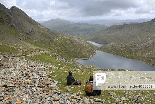 Drei Wanderer machen Rast und blicken auf die Landschaft  Mount Snowdon  Snowdonia National Park  Wales  Großbritannien