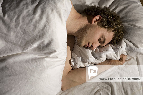 Junger Mann im Bett schlafend