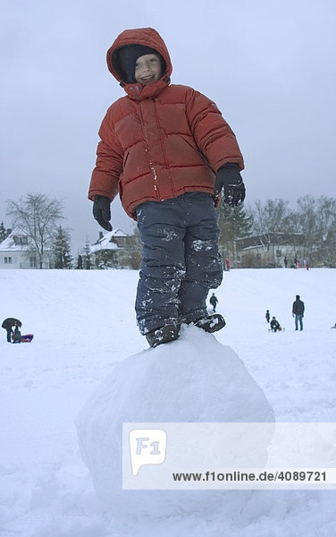 Six Year old boy standing on big snowball
