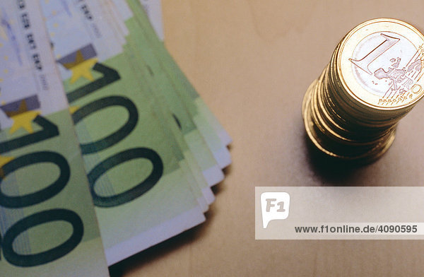 Stapel ein Euromünzen mit einem Stapel 100-Euroscheinen