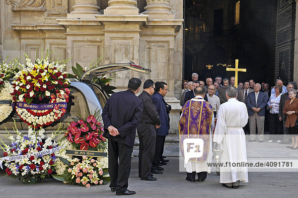 Priester mit goldenem Kreuz und Trauergaeste kommen aus der Kirche  Beerdigung  Leichenwagen mit Trauerkraenzen  Basilika Santa Maria  Elx  Elche  Costa Blanca  Spanien