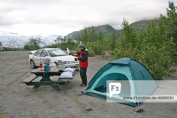 A woman prepares Dinner near the tent and car at the Matanuska glacier Alaska USA